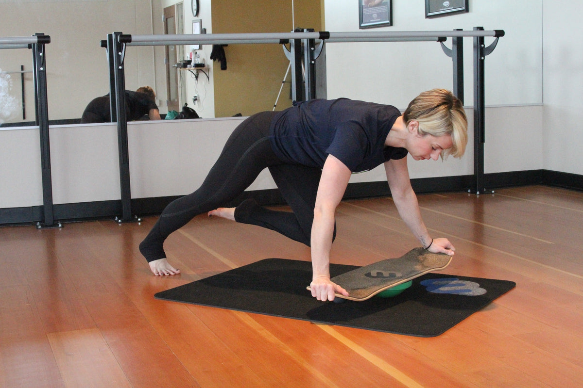 Woman doing mountain climbers with her hands on a Whirly Board in a dance studio
