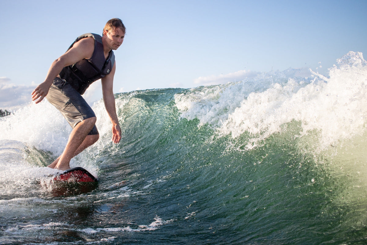 Man wakesurfing and carving a wave at golden hour
