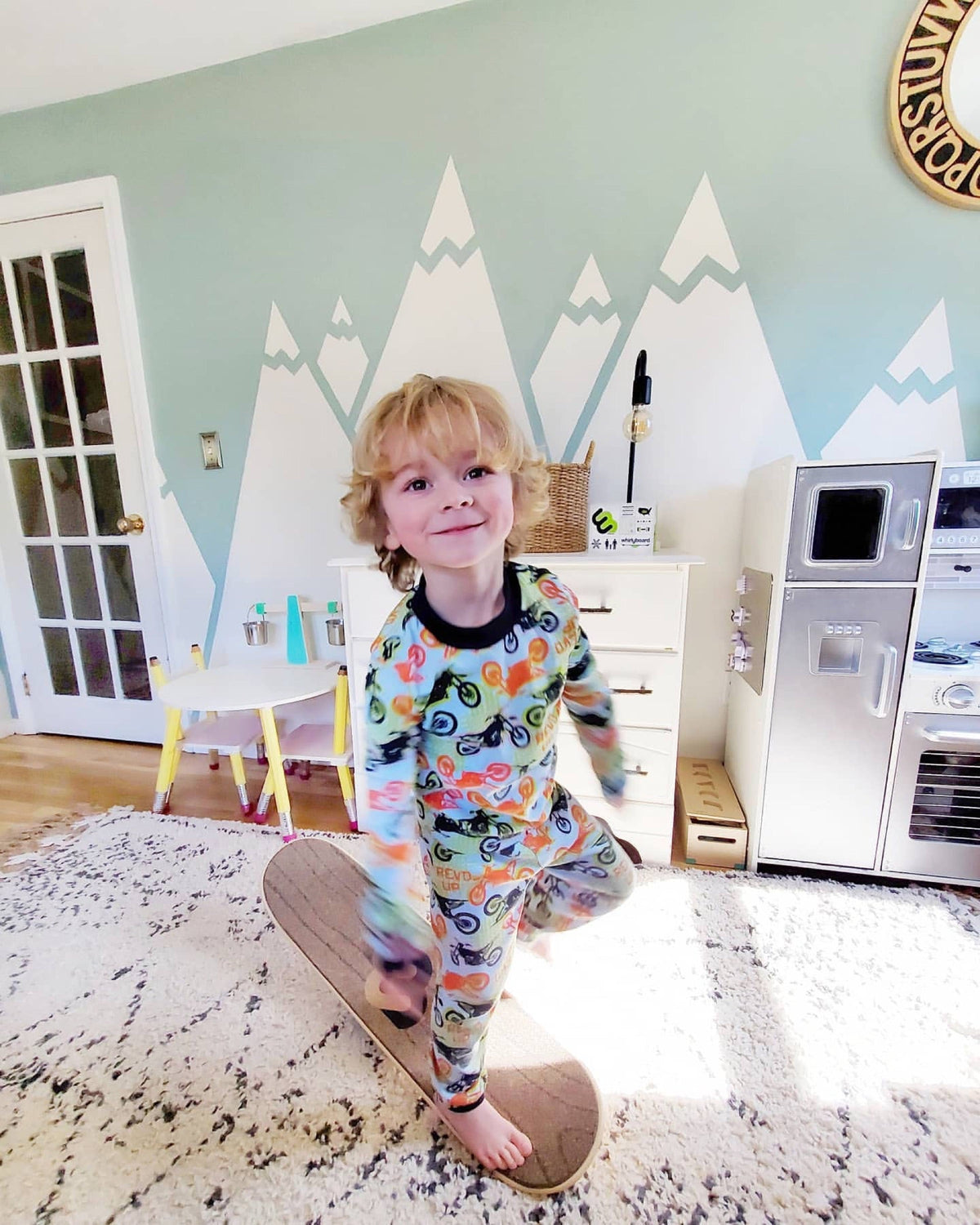 Young boy in pajamas balancing on a Whirly Board in his playroom