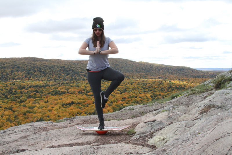 Woman in a yoga tree pose on a Whirly Board on a mountain overlook