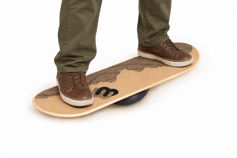 Feet in leather shoes balancing on a Whirly Desk Rider balance board with a cork mountain top