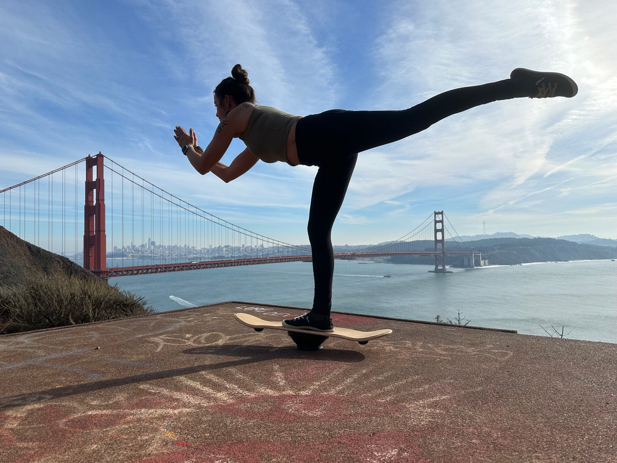 Joanna balancing in a yoga pose on a Whirly Board above the Golden Gate Bridge