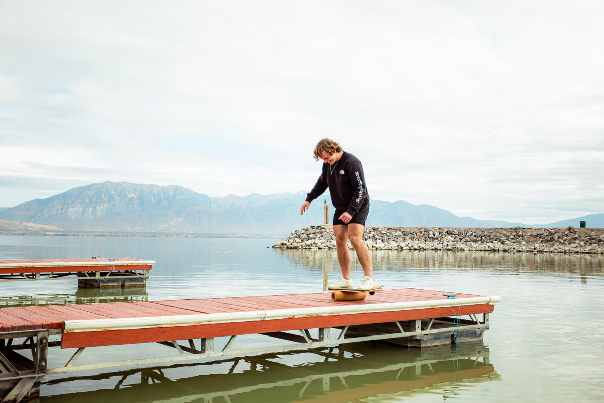A rider balancing on the Whirly Complete roller on a lake dock
