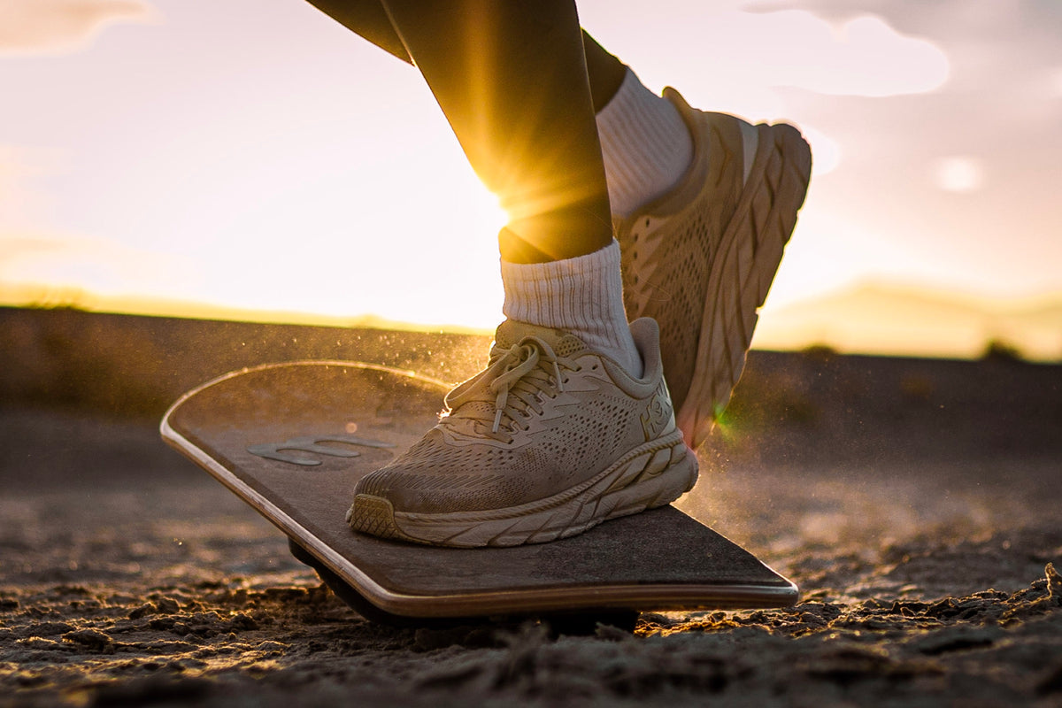 A sneaker on a Whirly Board kicking up salt at sunset
