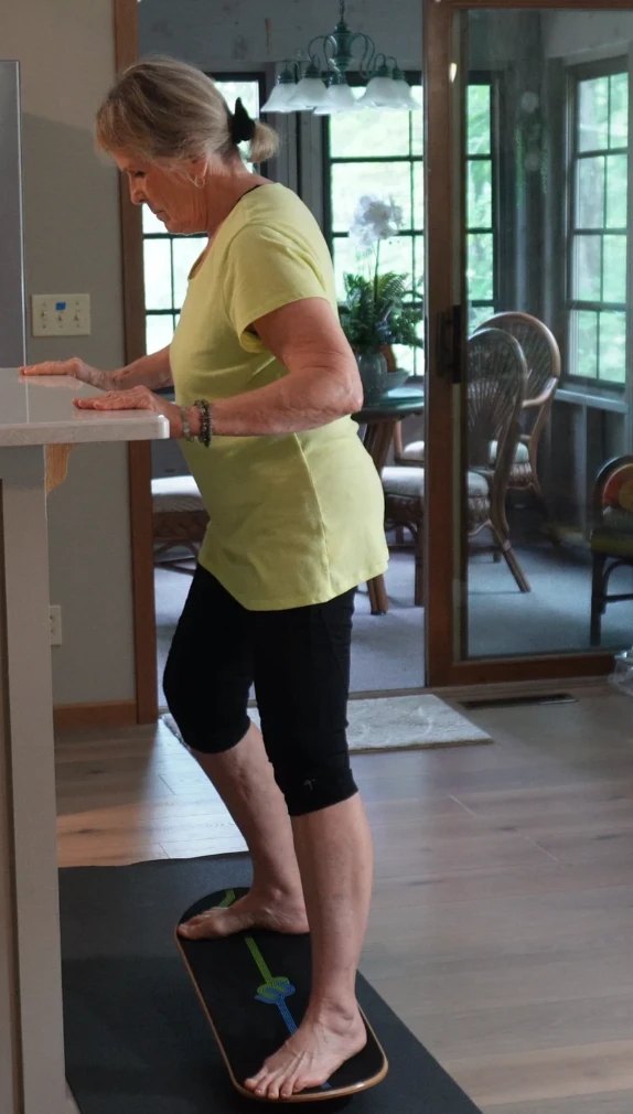 A woman balancing on a Whirly Complete at her kitchen counter
