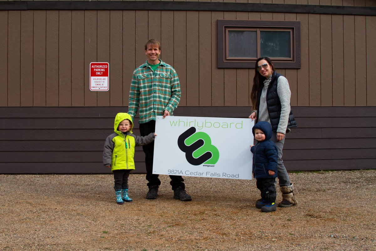 The family holding a Whirly Board sign outside the new facility