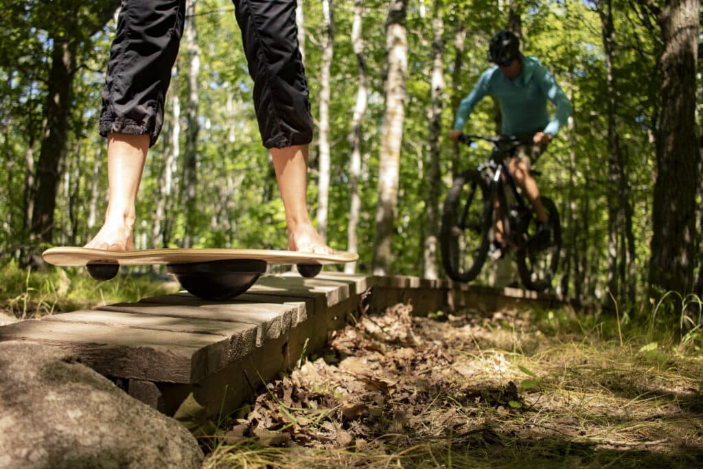 Man using a fitness balance board on a forest trail.