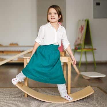 girl child doing a balance board workouts on a rocker board